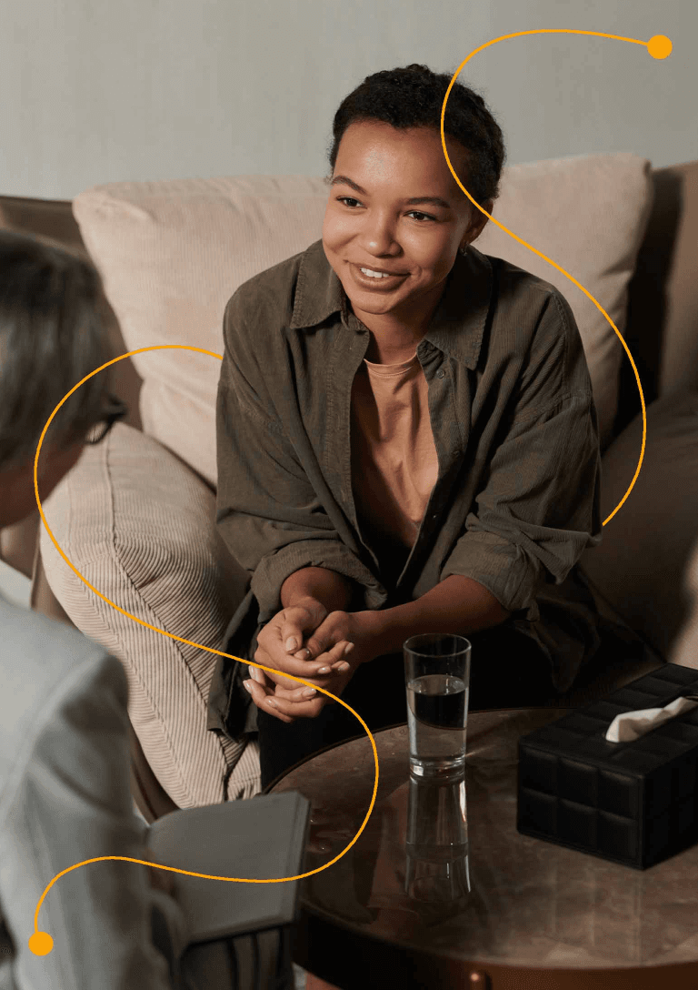 A woman and a man engaged in conversation while sitting on a couch