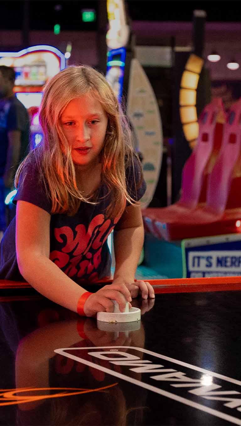 A little girl sitting at a table with a remote control