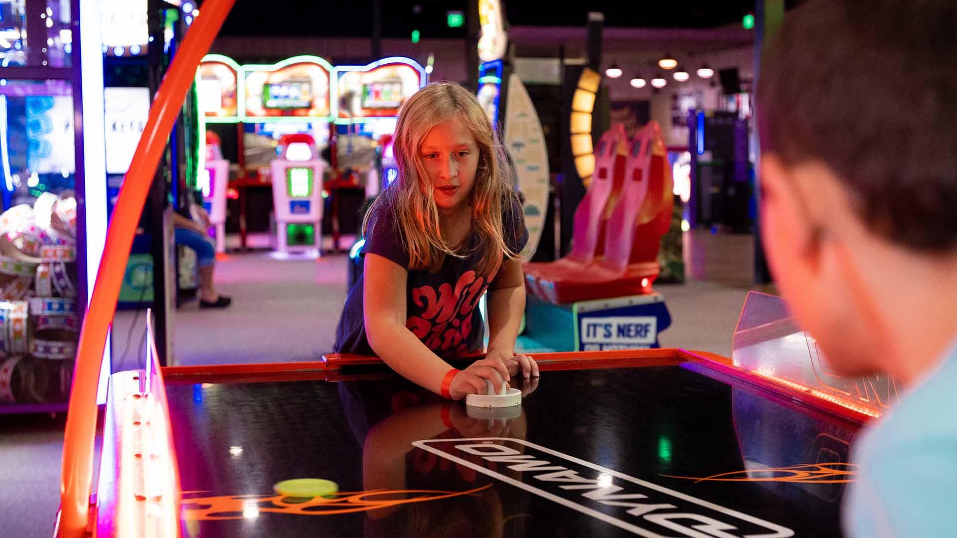 A little girl playing air hocker at a venu