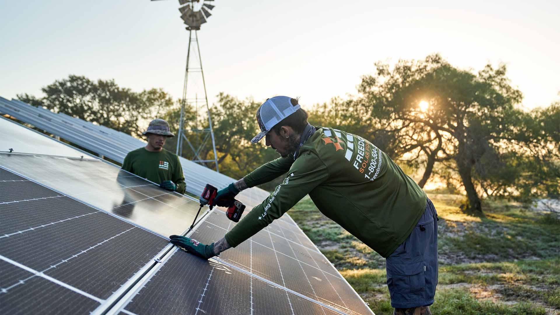 A team installing rooftop solar panels at dawn.