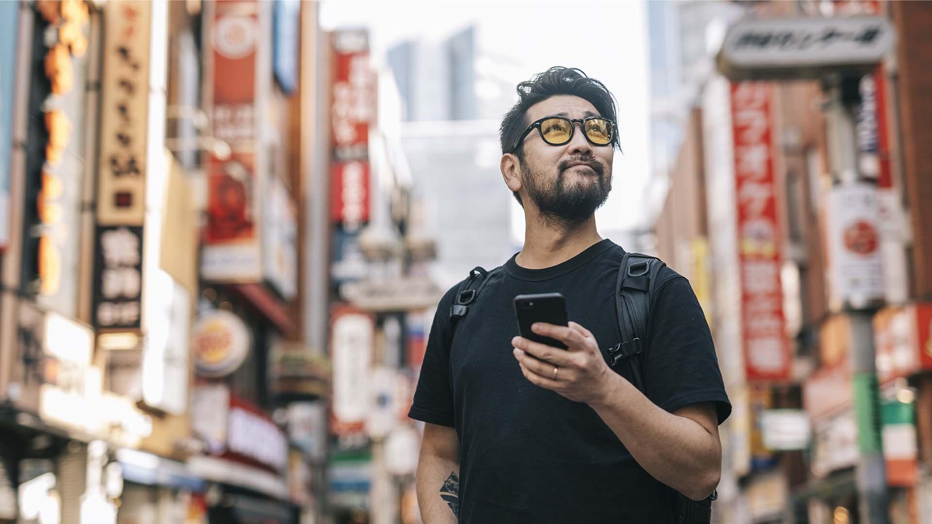 A man in the city holding a phone looking at the horizon.