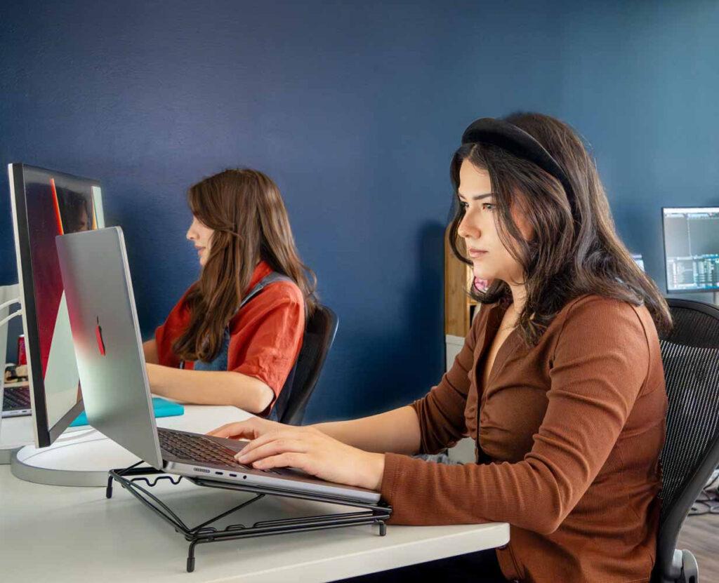 a woman sitting in front of a laptop computer