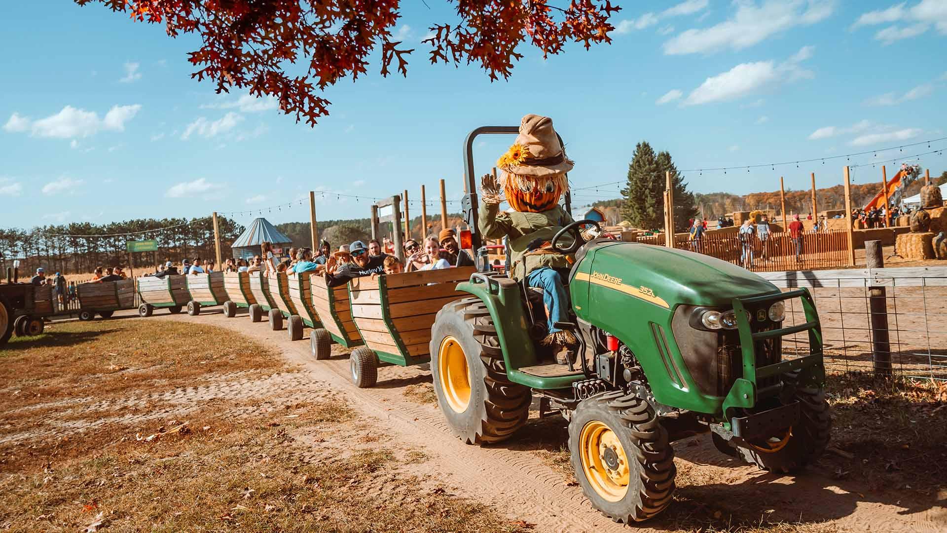 Tractor pull ride full of happy people and driven by Pumpkin Pete