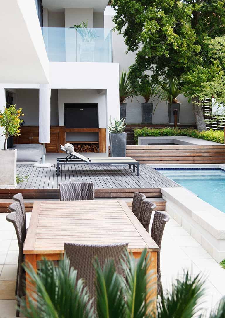 A luxury venue with pools, out-door tables, balconies, and greenery.