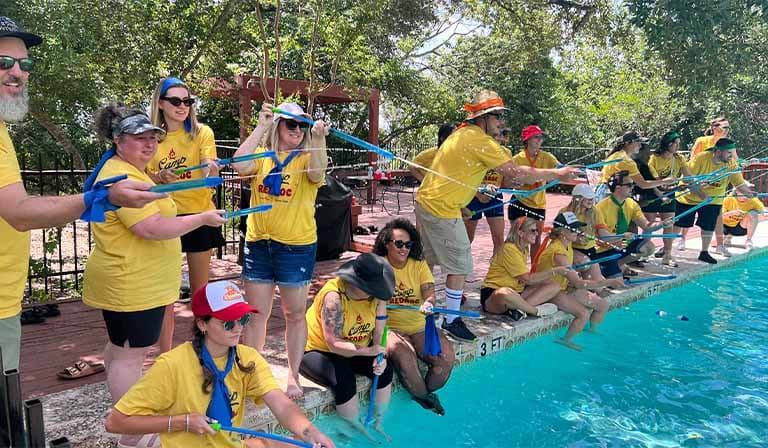 a group of people in yellow shirts standing next to a pool